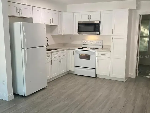 a white kitchen with cabinets stainless steel appliances and wooden floor