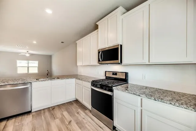 a kitchen with granite countertop a sink a stove and microwave with wooden floor