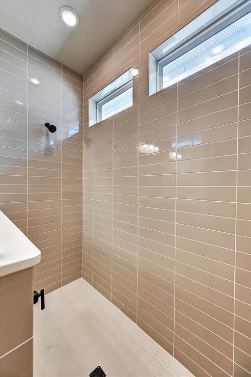 2237 Pika Road Northlake, TX 76247 - Photo 22 of 37 Walk-in shower featuring rectangular beige wall tiles, small hexagonal floor tiles, black shower fixtures, two high horizontal windows, and recessed ceiling lighting