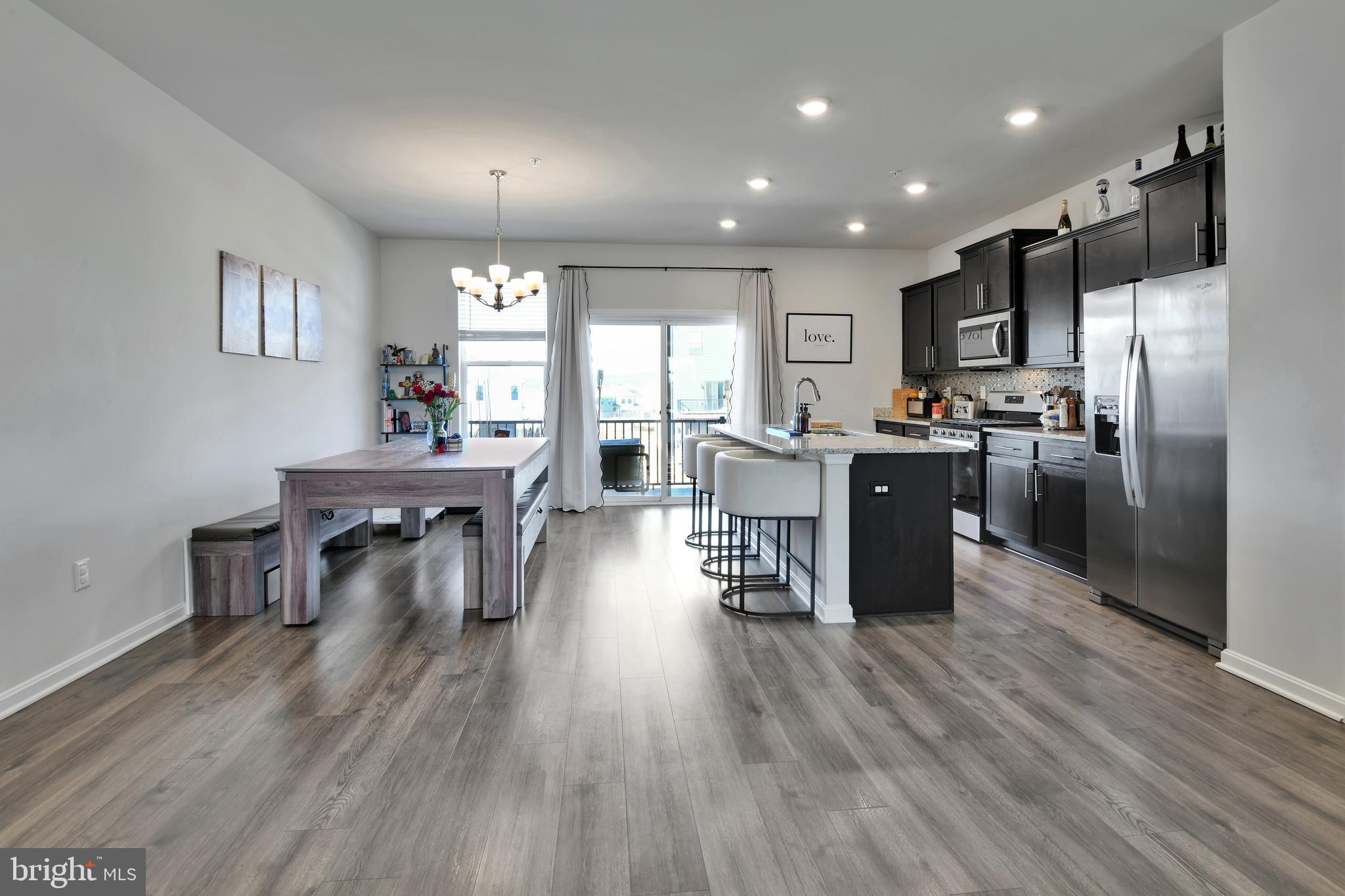 457 Tiller Street Frederick, MD 21701 - Photo 5 of 25 a kitchen with stainless steel appliances granite countertop a refrigerator a stove top oven a dining table and chairs with wooden floor