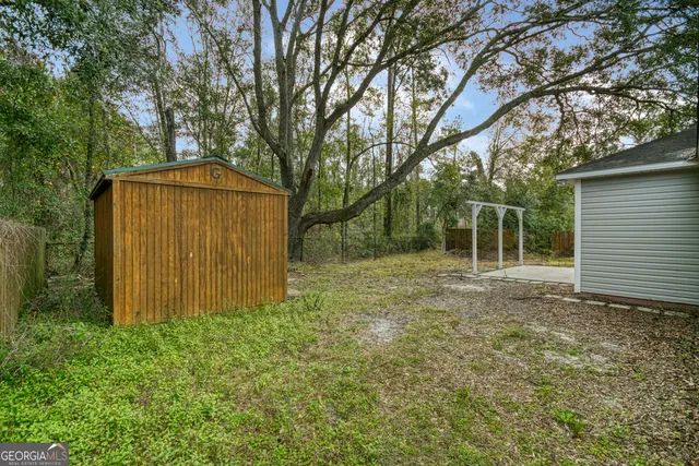 a view of backyard with large tree and wooden fence
