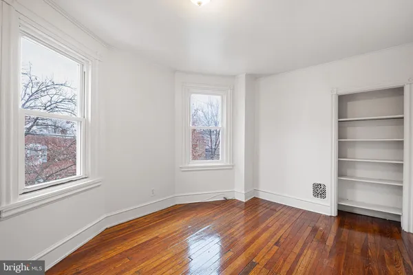 a view of an empty room with window and wooden floor