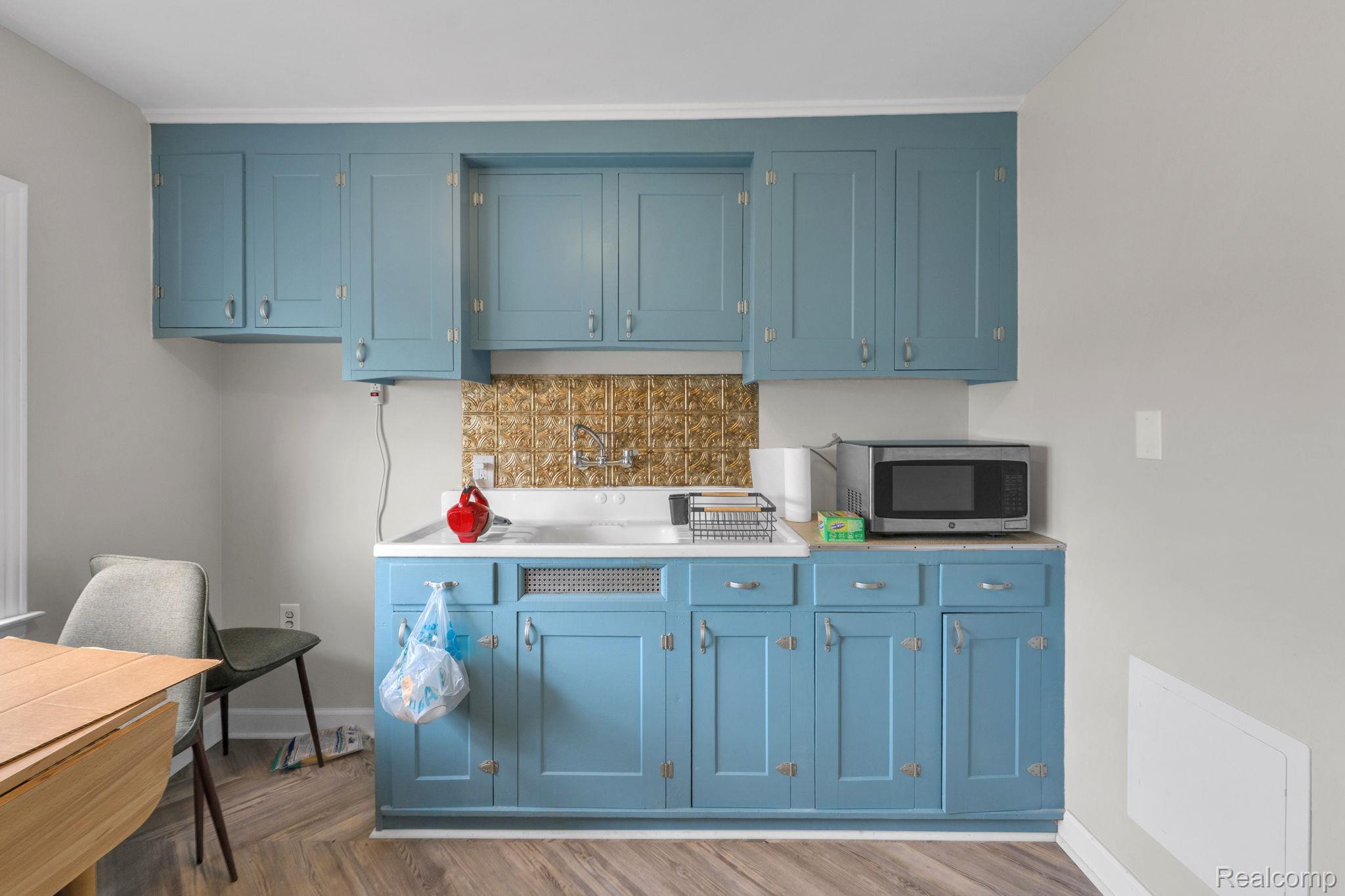7631 Maple Street Dearborn, MI 48126 - Photo 31 of 48 Kitchenette featuring blue painted cabinetry, wood-finish flooring, a white countertop, and a textured backsplash