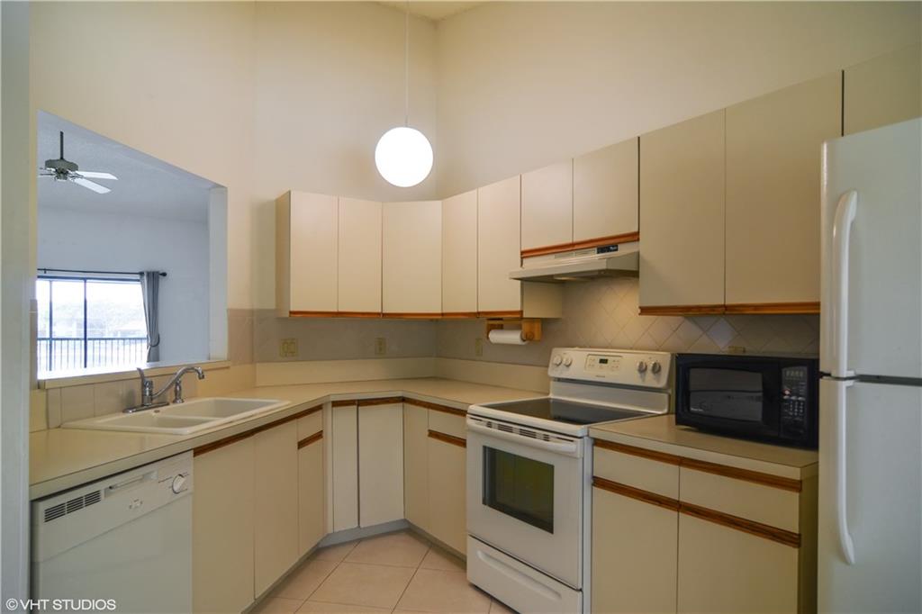 3410 Southeast Martinique Trace, Unit 202 Stuart, FL 34997 - Photo 4 of 15 a kitchen with granite countertop a sink stainless steel appliances and cabinets