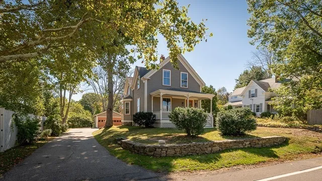 a view of a white house next to a yard with large trees