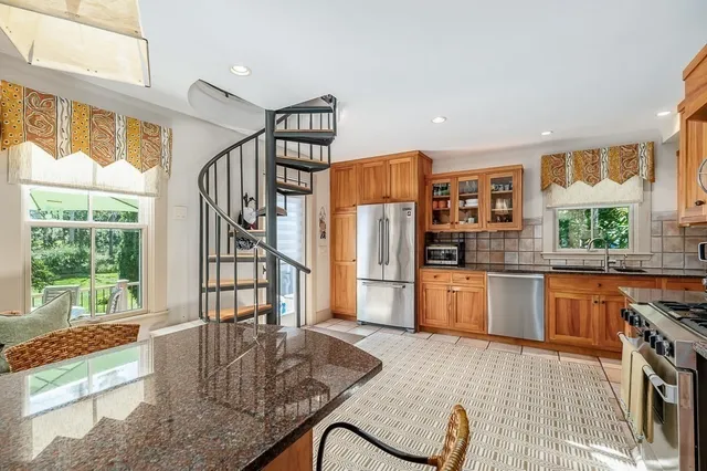 a kitchen with stainless steel appliances granite countertop a refrigerator a sink a stove and white cabinets with wooden floor