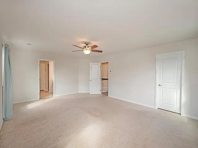 a view of an empty room with a chandelier fan