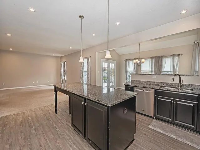 a kitchen with stainless steel appliances granite countertop a sink a stove and a wooden floors