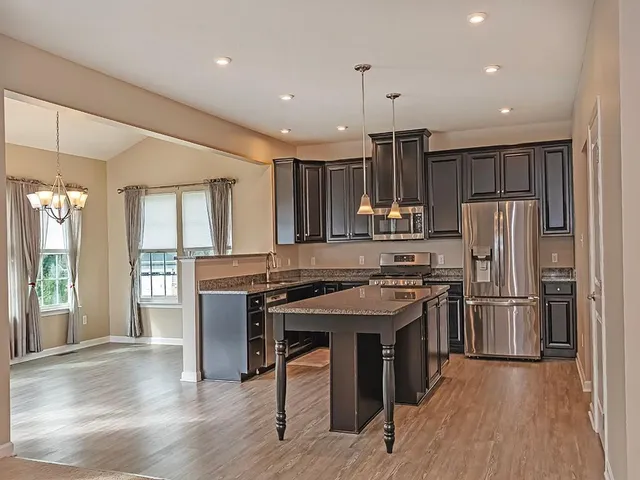 a kitchen with stainless steel appliances granite countertop a refrigerator a stove and a wooden floors