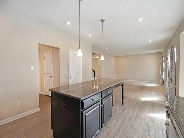 a kitchen with stainless steel appliances granite countertop a refrigerator a sink and wooden floor