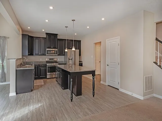 a kitchen with kitchen island wooden floors appliances and cabinets