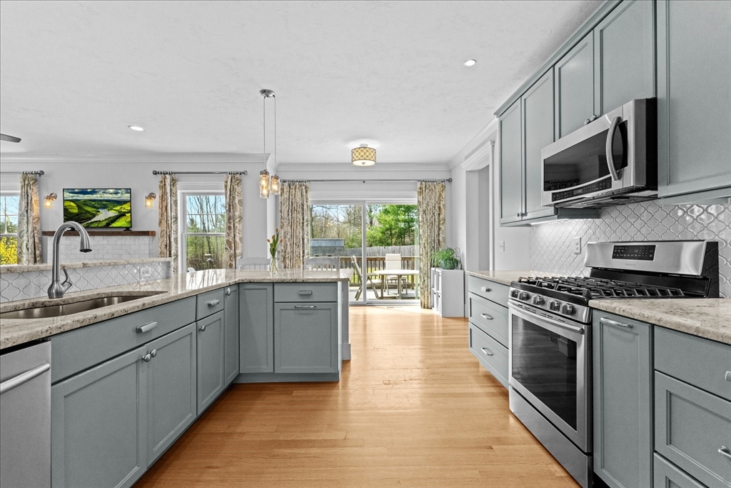 50 Quabbin Path Sutton, MA 01590 - Photo 16 of 42 a kitchen with stainless steel appliances granite countertop a stove top oven a sink dishwasher a microwave oven and a dining table with wooden floor