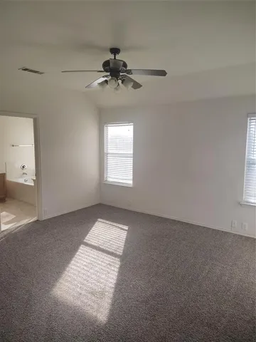 an empty room with windows and fan
