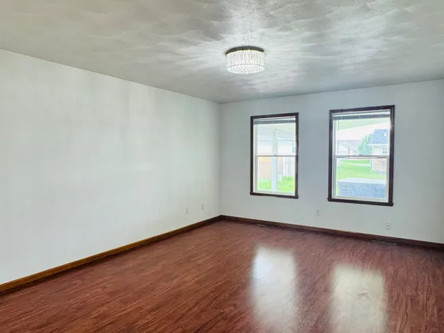 a view of an empty room with wooden floor and windows