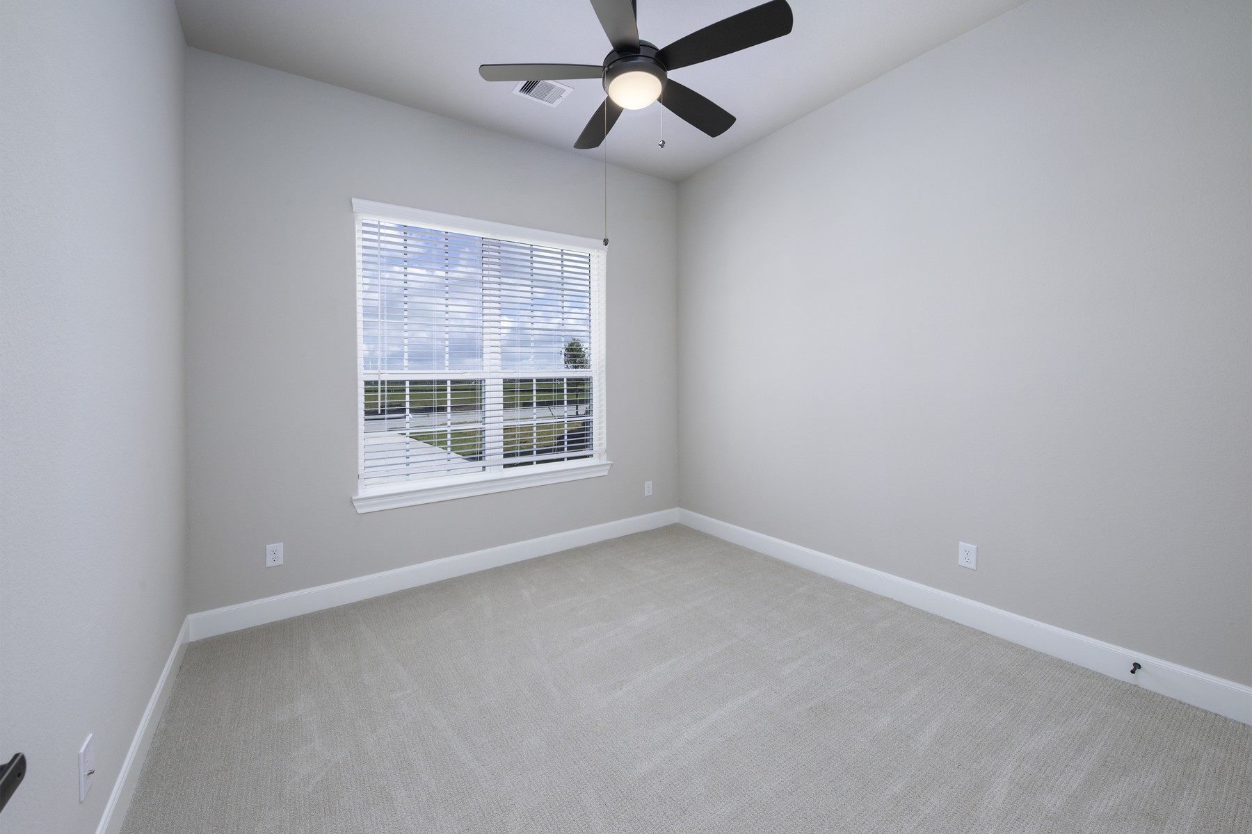 10622 Sutter Crk Drive Rosharon, TX 77583 - Photo 15 of 28 Welcome to Secondary Bedroom 2! This bright and inviting space mirrors the home's modern aesthetic with plush carpeting, a stylish ceiling fan, and a large window that offers a clear view of the neighborhood.