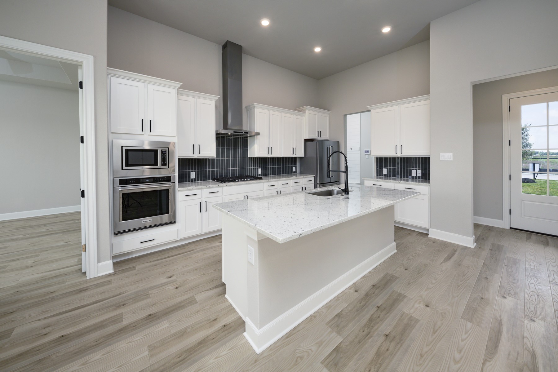 10622 Sutter Crk Drive Rosharon, TX 77583 - Photo 7 of 28 The designer kitchen stands out with its striking vertical subway tile backsplash, sleek stainless steel vent hood, and built-in appliances that blend seamlessly with the crisp white cabinetry.