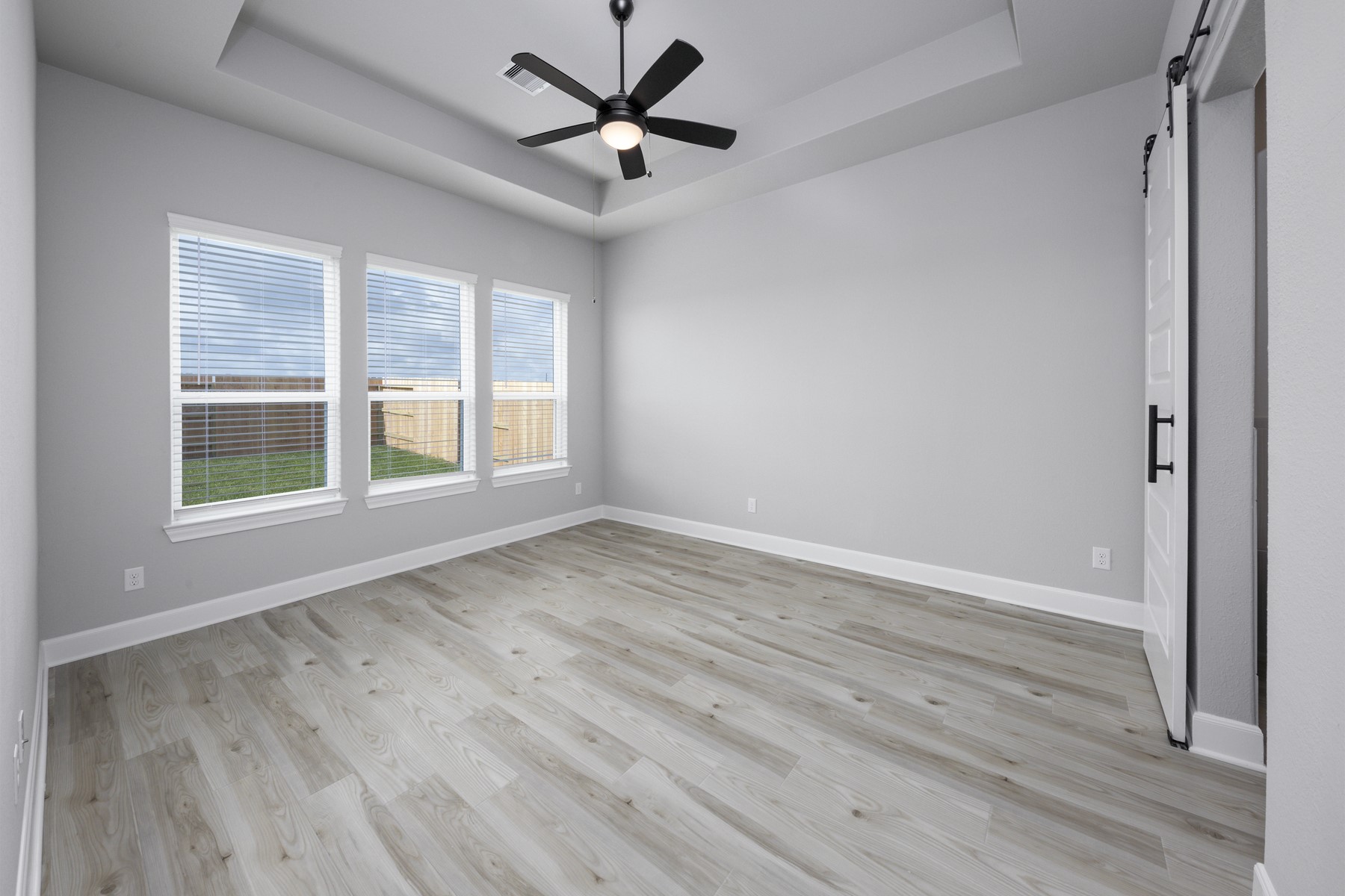 10622 Sutter Crk Drive Rosharon, TX 77583 - Photo 9 of 28 The master bedroom boasts a sophisticated tray ceiling and a trio of windows that fill the space with natural light, while the trendy sliding barn door leads the way to your private ensuite.