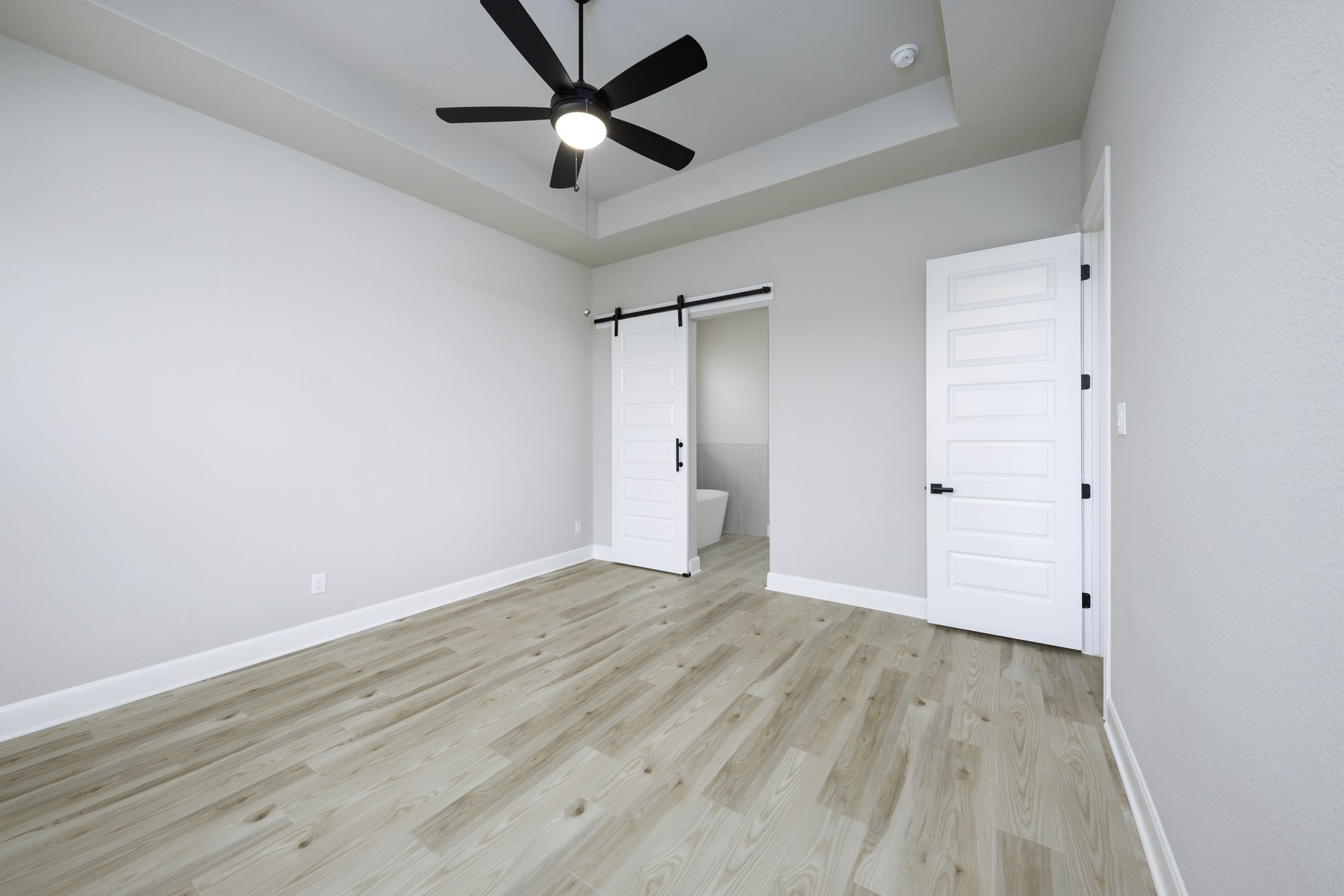 10622 Sutter Crk Drive Rosharon, TX 77583 - Photo 10 of 28 This spacious master bedroom offers a perfect blend of comfort and style, featuring clean lines, a dramatic tray ceiling, and a charming sliding barn door that leads directly into your spa-like master bath.