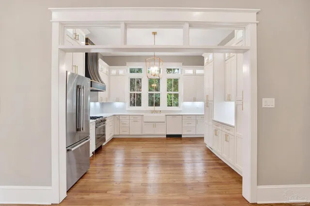 a hallway with white cabinets and wooden floor
