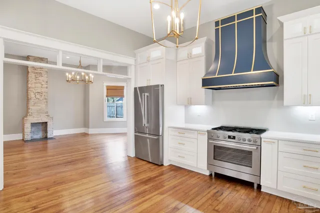 a kitchen with stainless steel appliances granite countertop a refrigerator a stove and a wooden floors