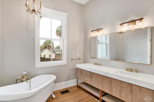 a bathroom with a tub double vanity sink and mirror