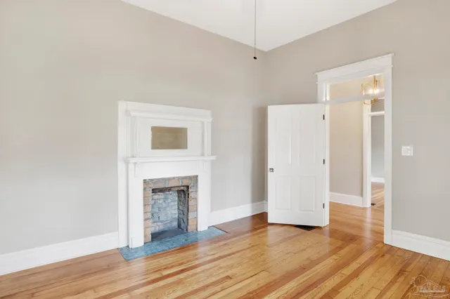 an empty room with wooden floor and fireplace