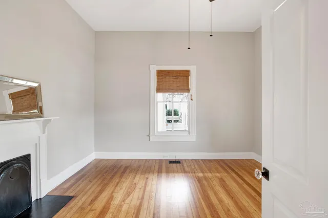 a view of an empty room with wooden floor and a window