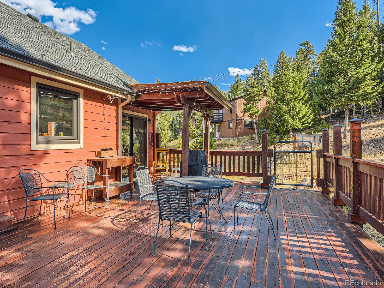 7051 Ski Trail Evergreen, CO 80439 - Photo 29 of 39 a view of a patio with table and chairs with wooden floor and fence