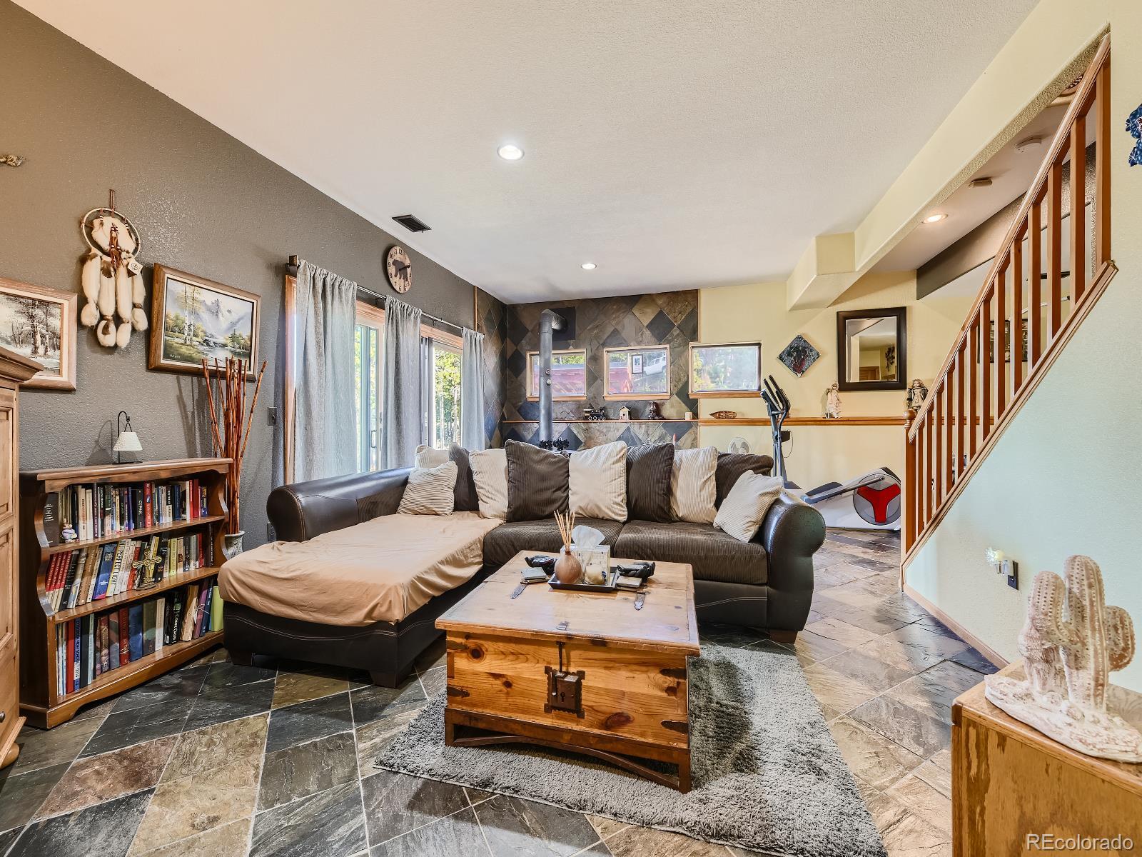 7051 Ski Trail Evergreen, CO 80439 - Photo 8 of 39 a living room with furniture a rug and a book shelf