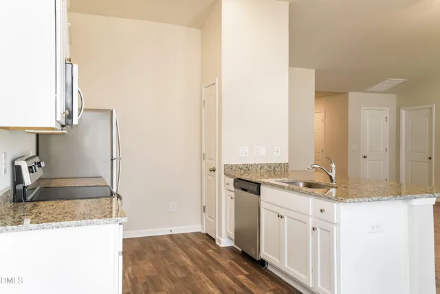 a kitchen with kitchen island granite countertop a sink stove and refrigerator
