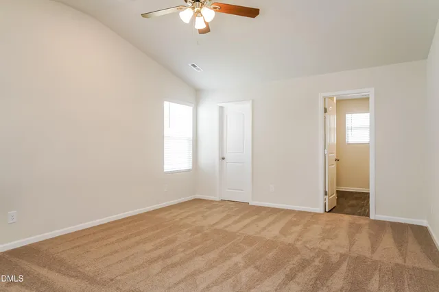 an empty room with a chandelier fan and windows