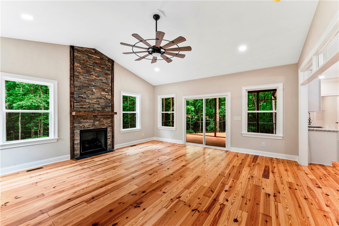 110 Gabriel Way Pickens, SC 29671 - Photo 13 of 48 A spacious living area with warm wood flooring and a floor-to-ceiling stone fireplace creates a comfortable ambiance.