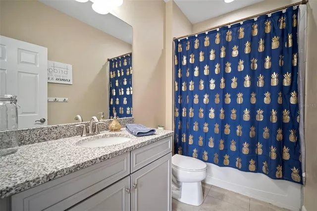 a bathroom with a granite countertop bathtub sink vanity mirror and toilet