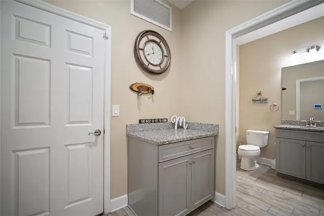 a bathroom with a granite countertop toilet a sink and a mirror