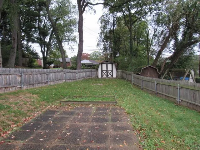 a view of a backyard with large trees and wooden fence