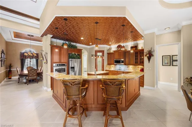 a dining hall with stainless steel appliances kitchen island granite countertop a table and chairs