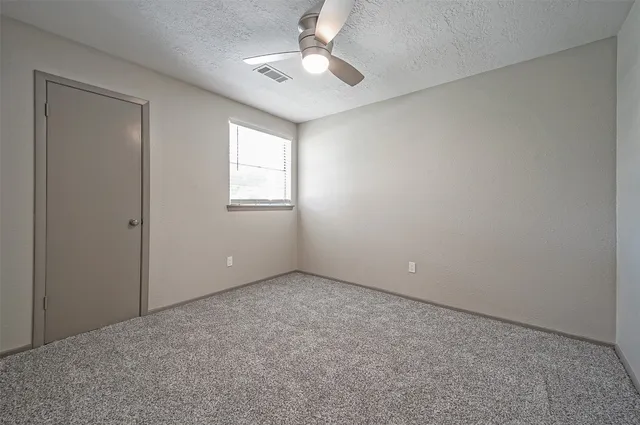 an empty room with windows and fan