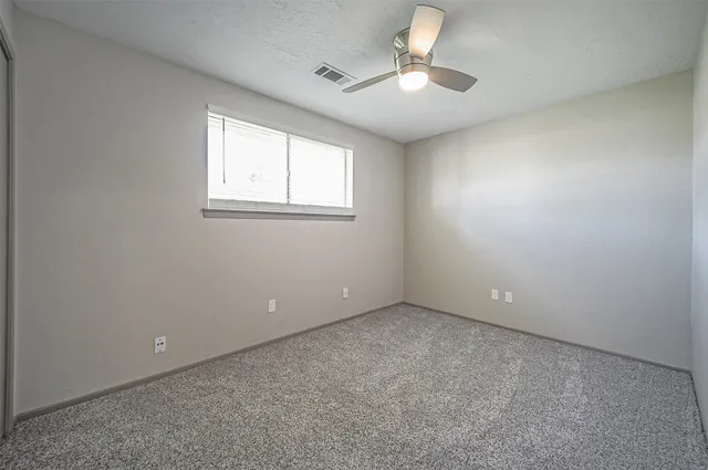 an empty room with a chandelier fan and windows