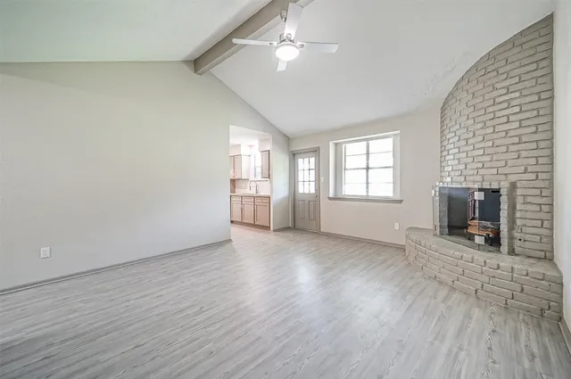 an empty room with windows fireplace and wooden floor