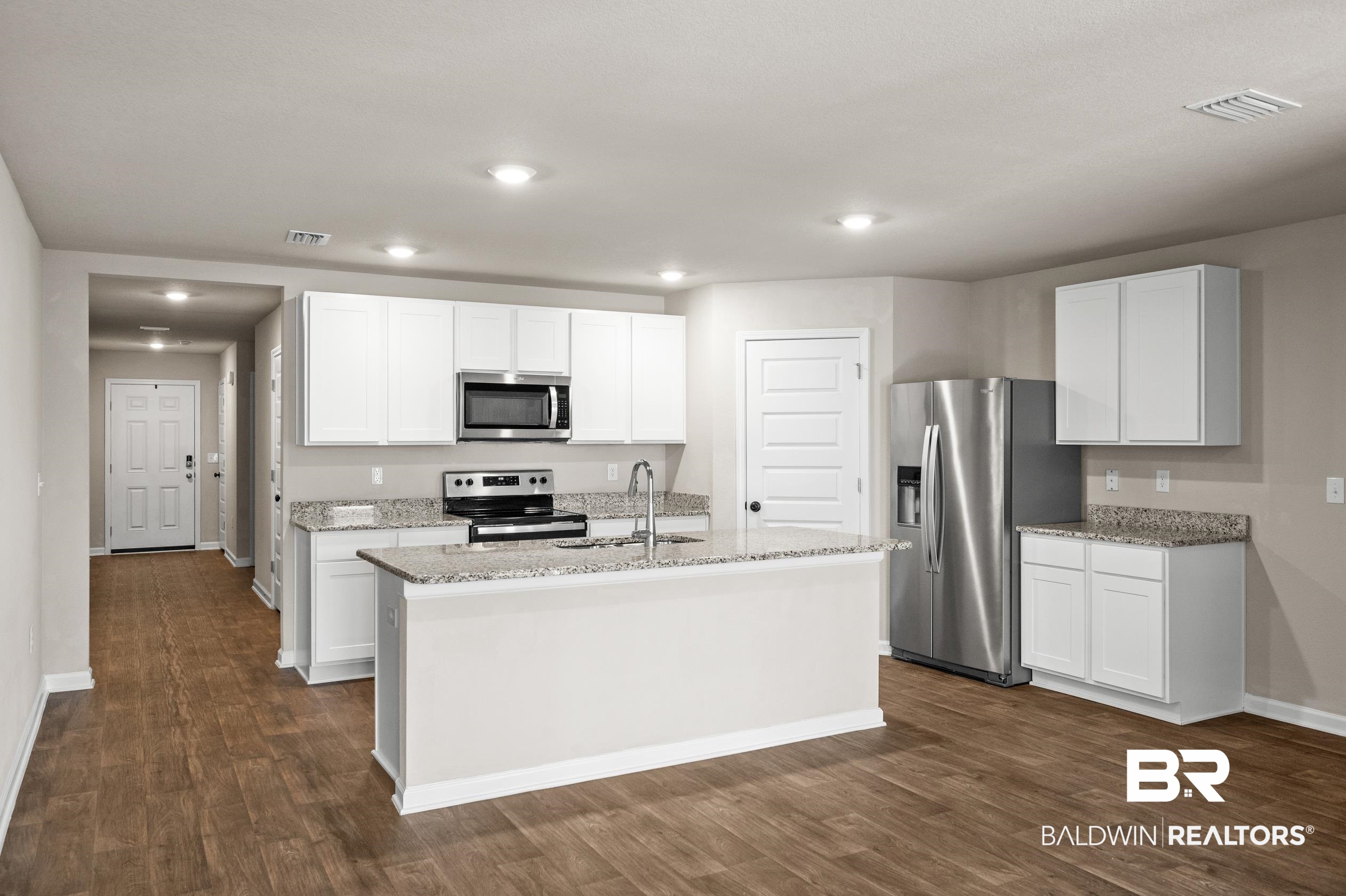 10353 Zenyatta Loop Daphne, AL 36526 - Photo 5 of 33 Kitchen featuring appliances with stainless steel finishes, dark hardwood / wood-style flooring, white cabinets, and a center island with sink