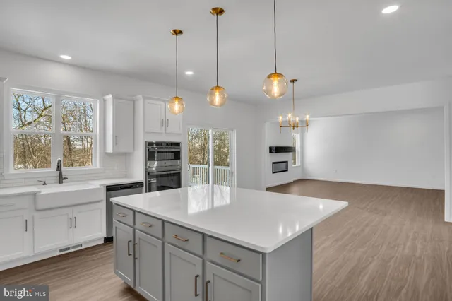 a kitchen with a wooden floor and a view of living room