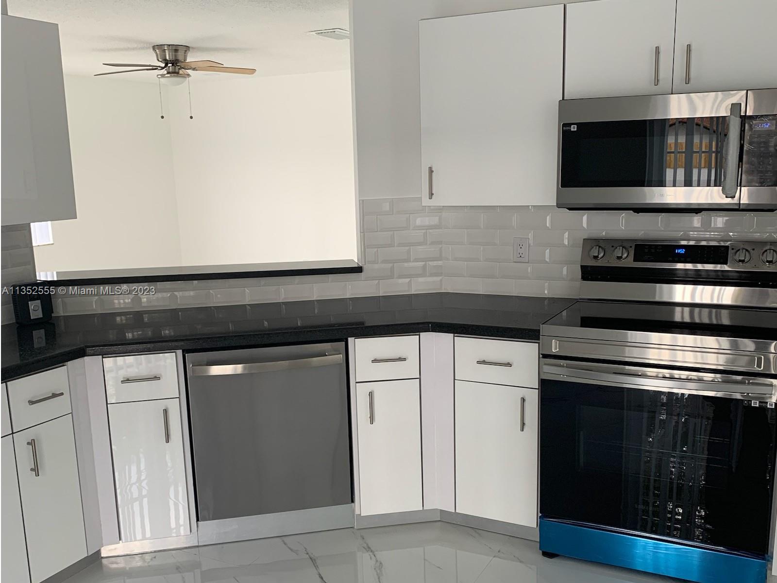 11111 Southwest 147th Court Miami, FL 33196 - Photo 6 of 20 a kitchen with granite countertop white cabinets stainless steel appliances and sink