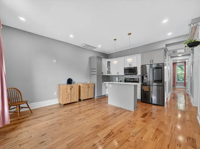 a kitchen with stainless steel appliances kitchen island granite countertop a refrigerator and a stove top oven