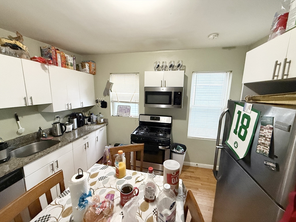 3977 Washington Street, Unit 1 Boston, MA 02131 - Photo 2 of 13 a kitchen with stainless steel appliances kitchen island granite countertop a sink and cabinets