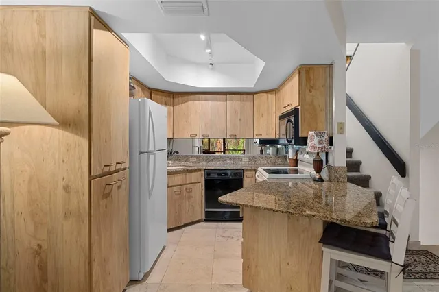 a kitchen with stainless steel appliances granite countertop a sink refrigerator and cabinets