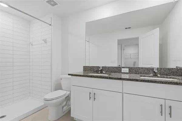a bathroom with a granite countertop sink a toilet a mirror and shower