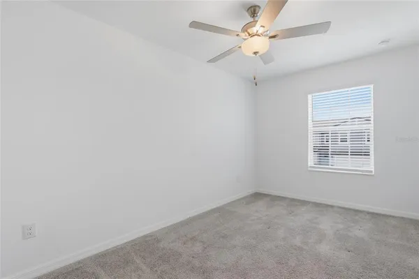 an empty room with a window and a fan