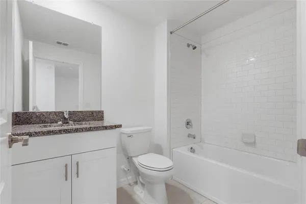 a bathroom with a granite countertop toilet sink and mirror