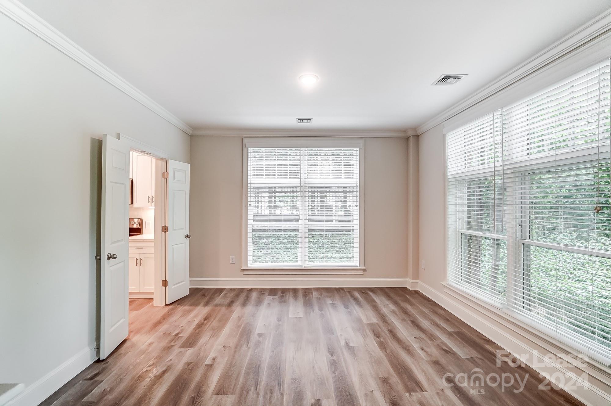 1301 Queens Road, Unit 205 Charlotte, NC 28207 - Photo 12 of 23 a view of an empty room with wooden floor and a window