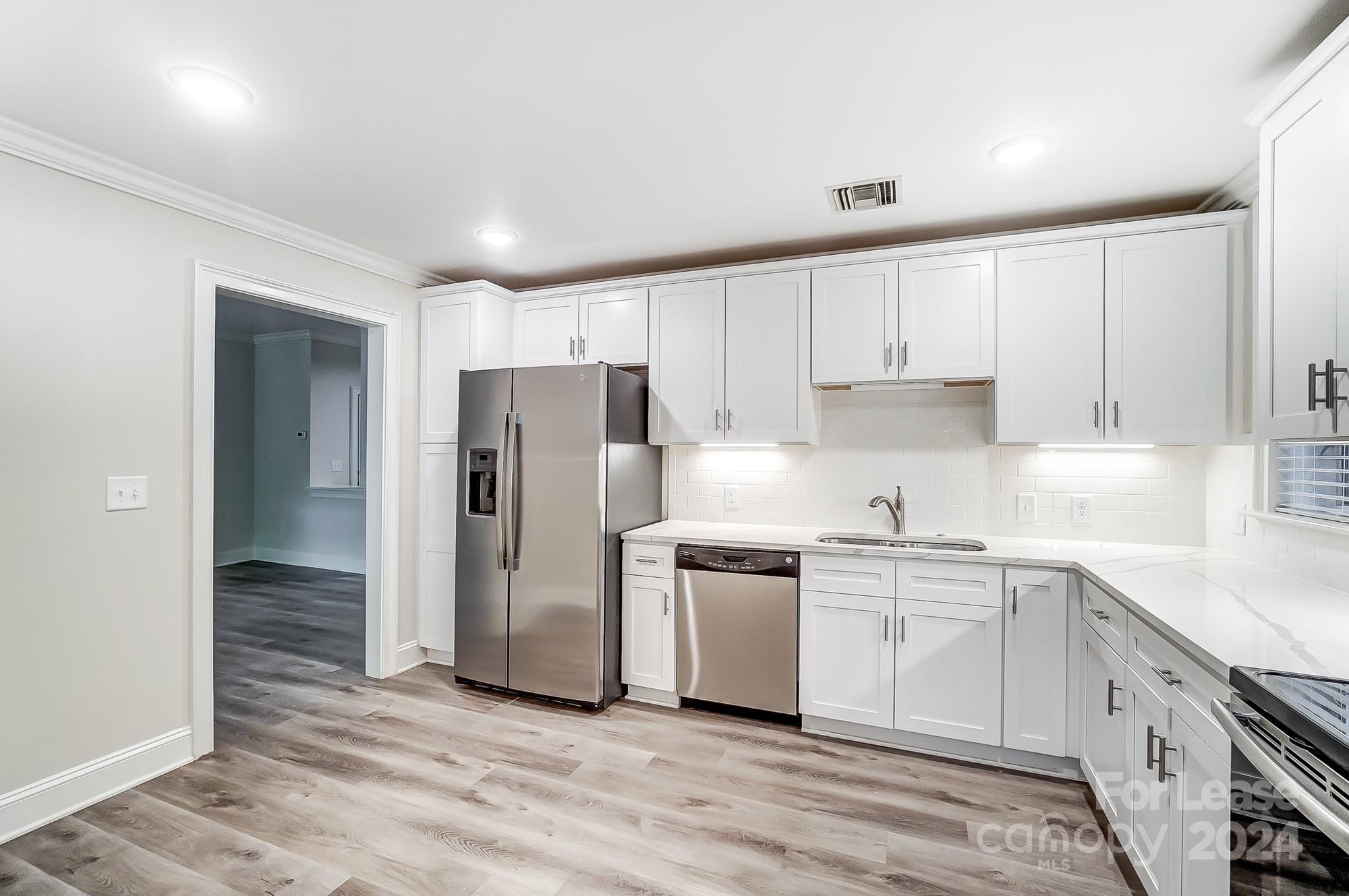 1301 Queens Road, Unit 205 Charlotte, NC 28207 - Photo 15 of 23 a kitchen with white cabinets and stainless steel appliances